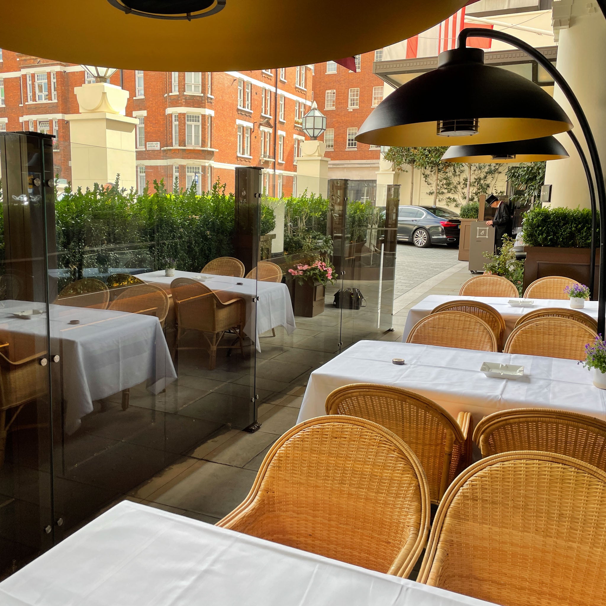 Image of a sheltered outdoor cafe space featuring glass windbreakers