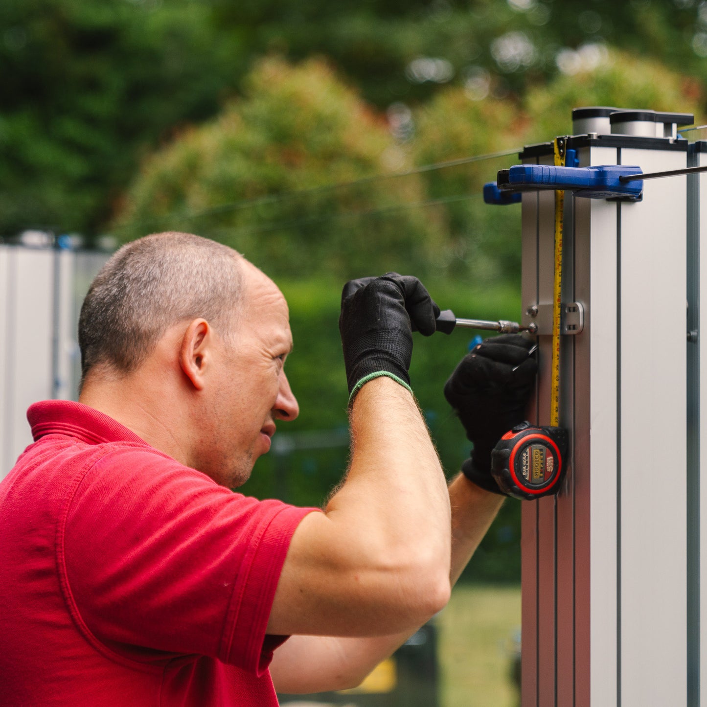 Man measuring alignment of metal fixings on a metal post