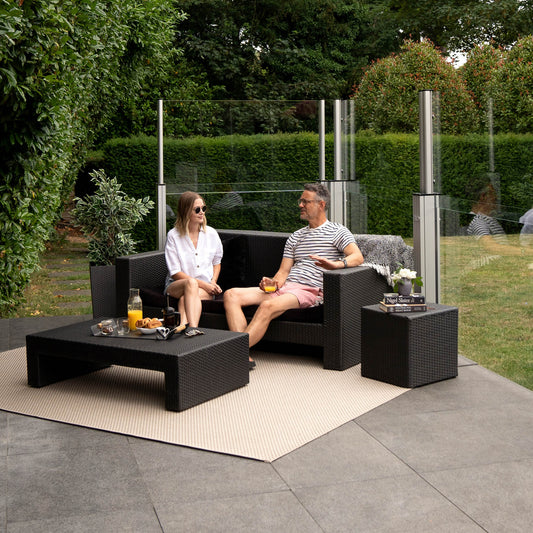 man and women having breakfast on a patio sheltered by glass balustrades