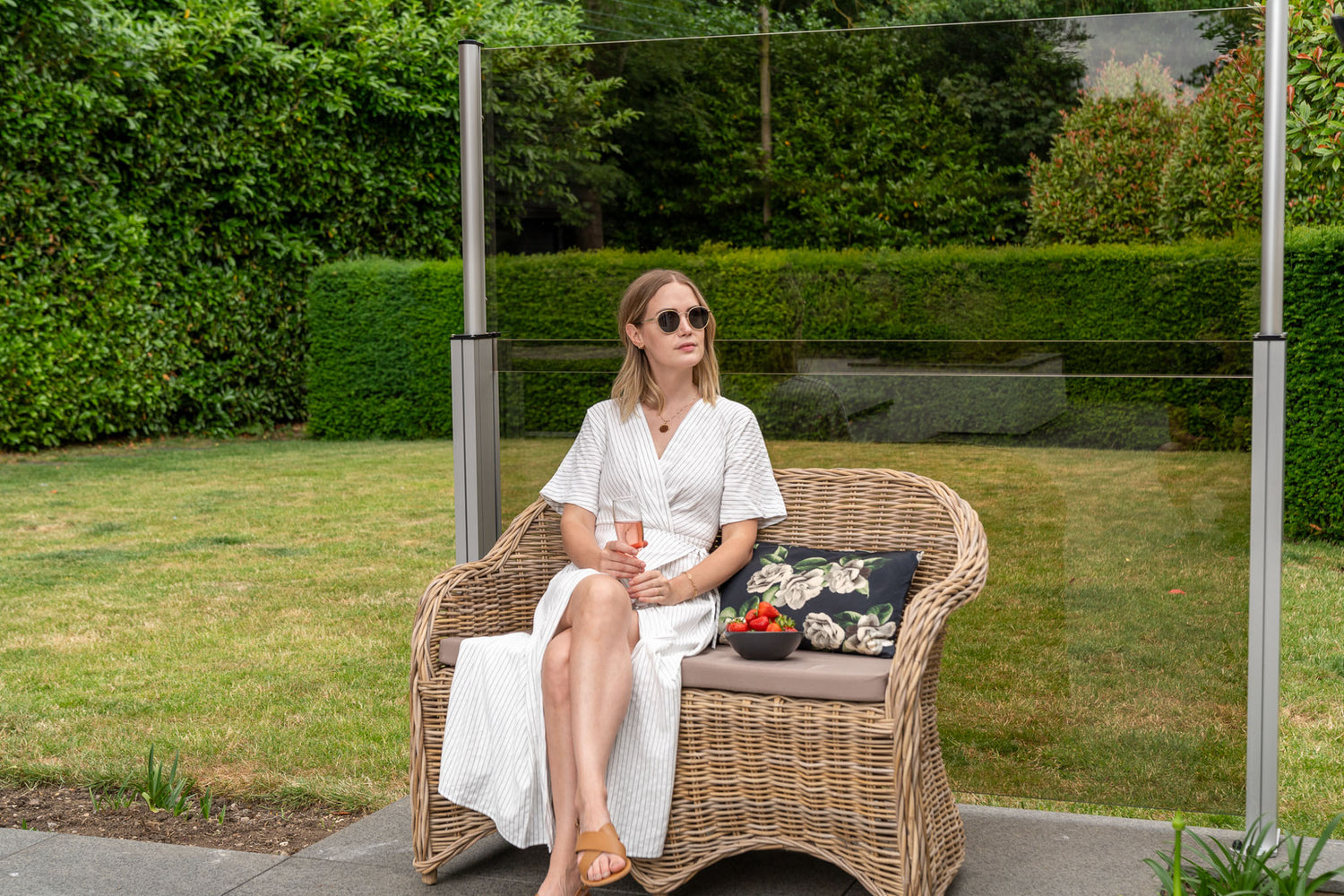 women sat on wicker chair in front of a golden tinted glass balustrade