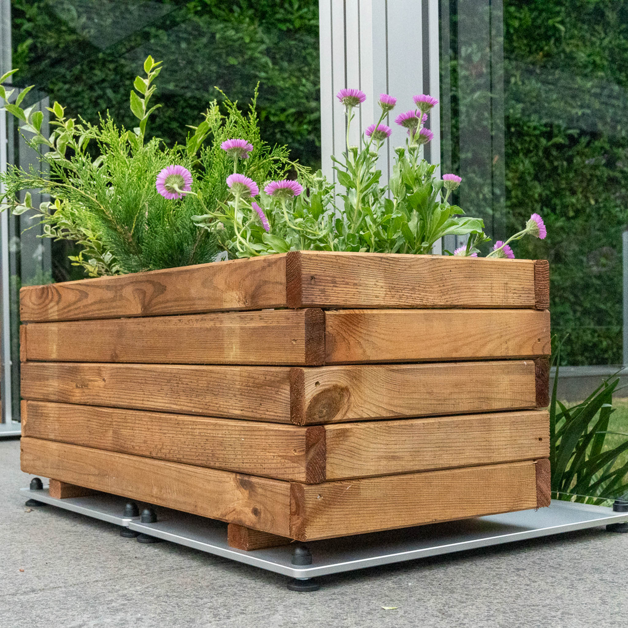 A wooden square planter sat on a footed base plate 