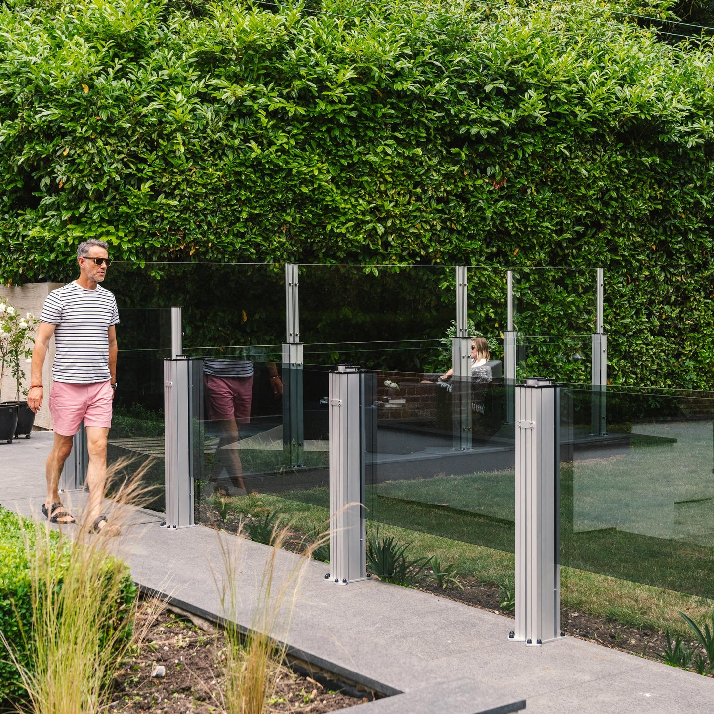 Man walking along a patio lined with glass balustrades