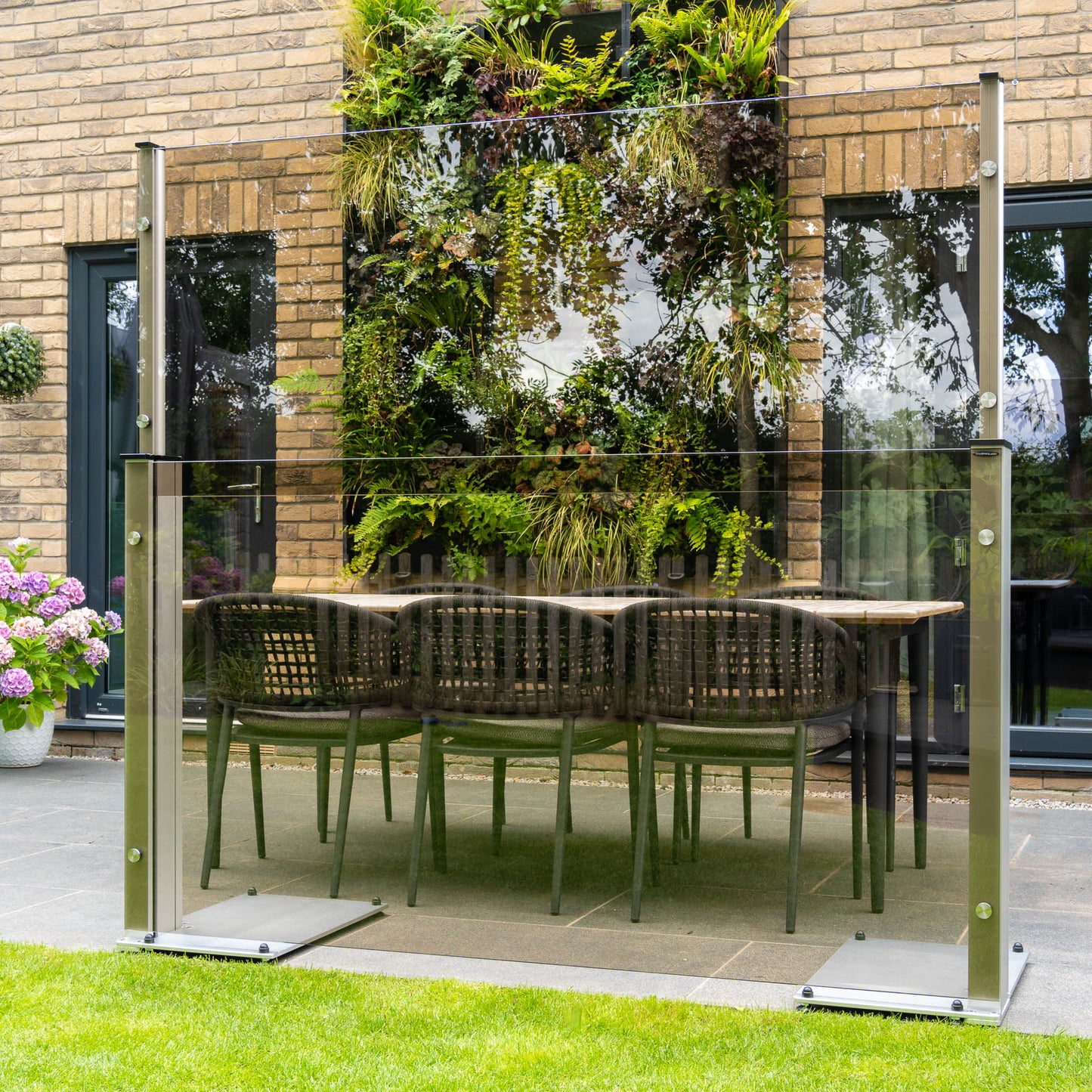 Extended to 6ft bronze tinted glass patio screen stood infront of a garden dining set