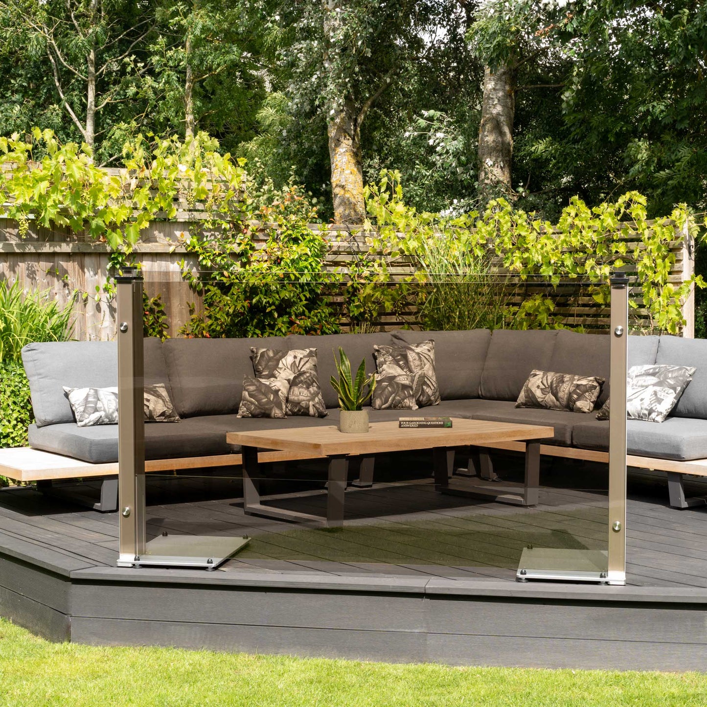 Bronze tinted glass balustrade on a decked platform in front of a garden sofa