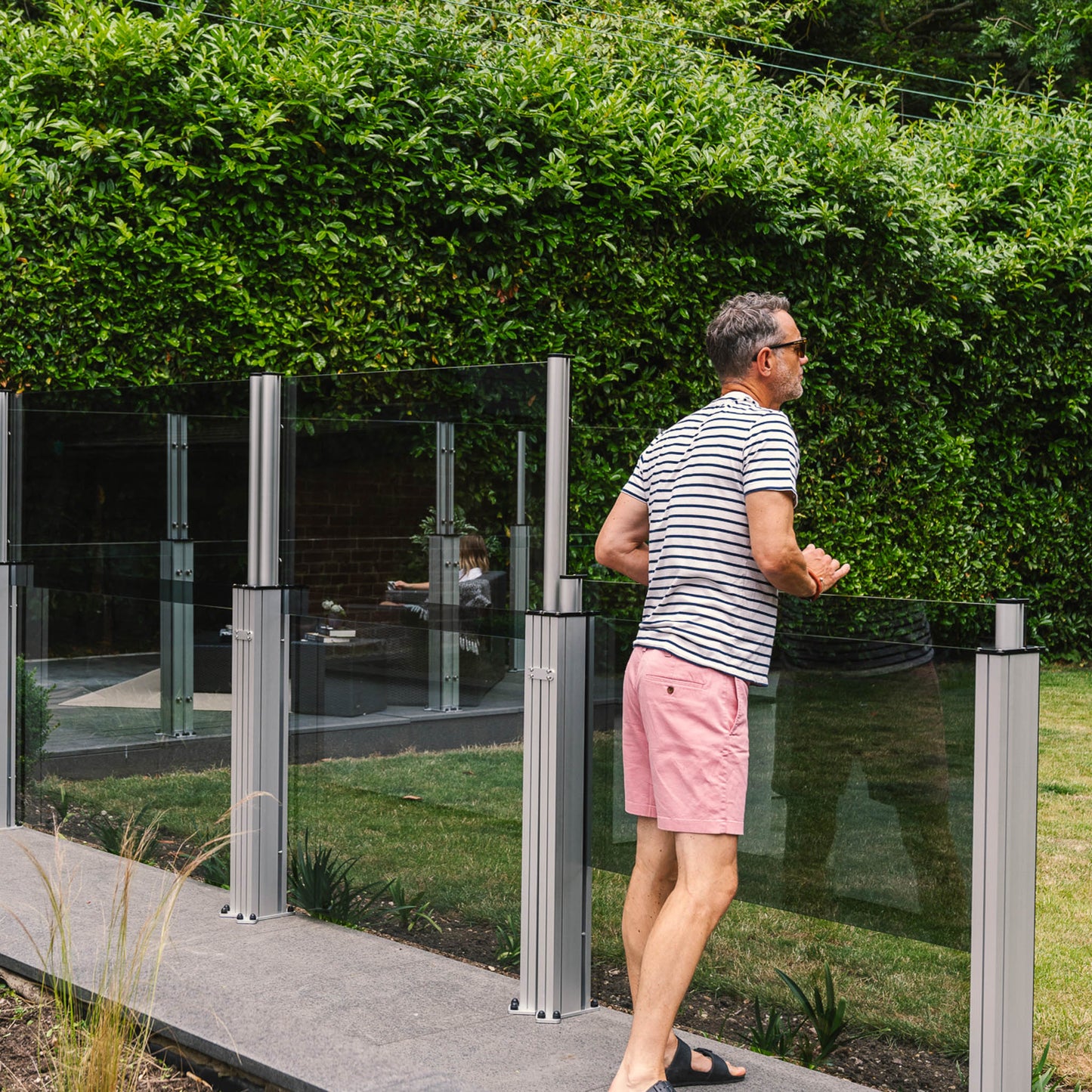 Man pushing down the glass panel on a run of windbreakers lining a walkway