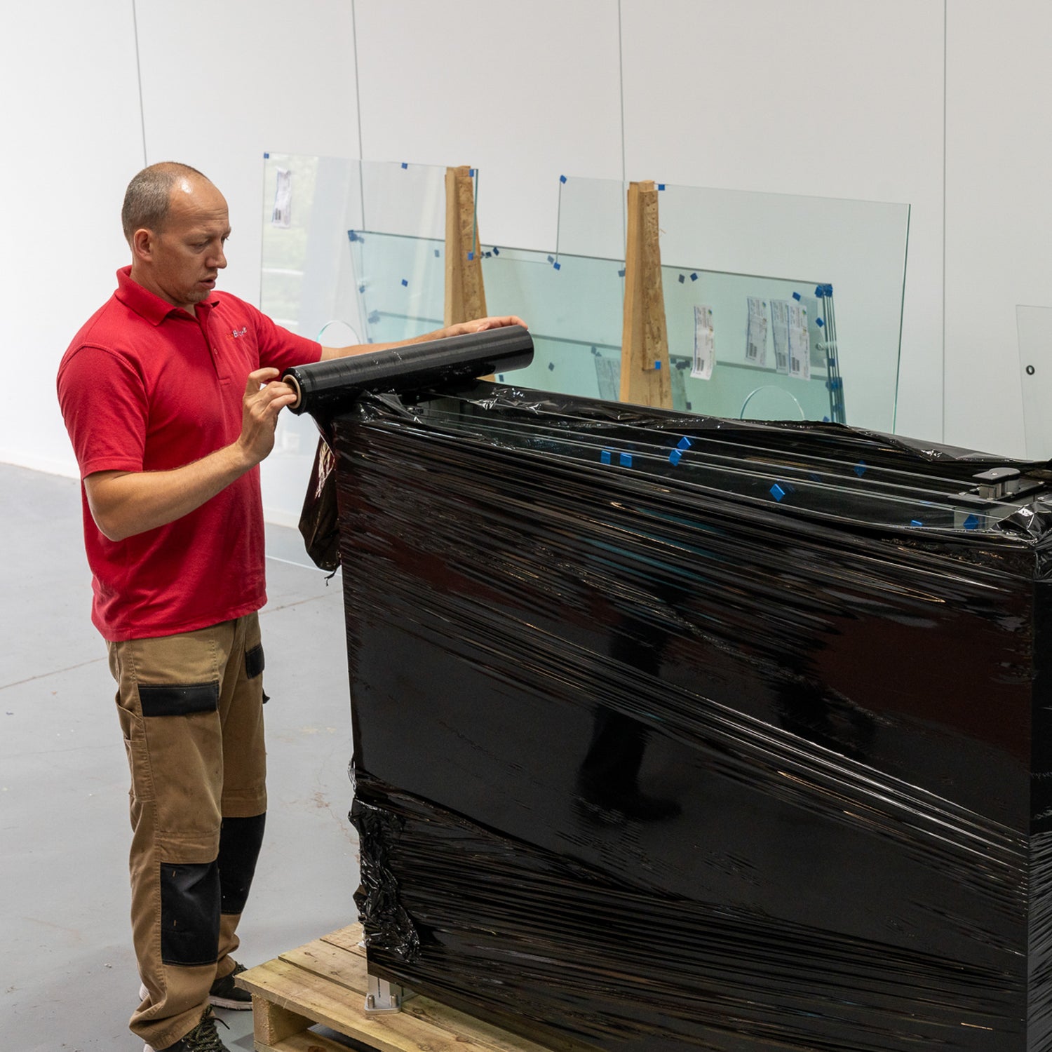 Delivery man wrapping a customer order of glass screens ready for shipping
